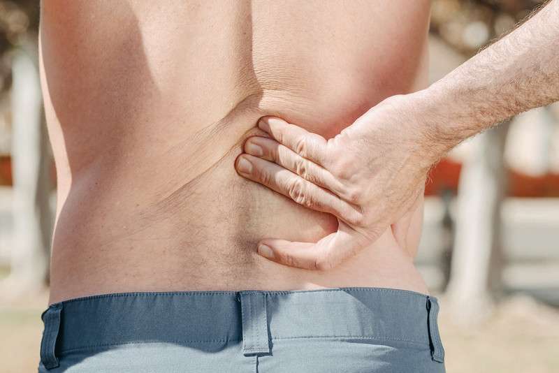 man holding his back in pain